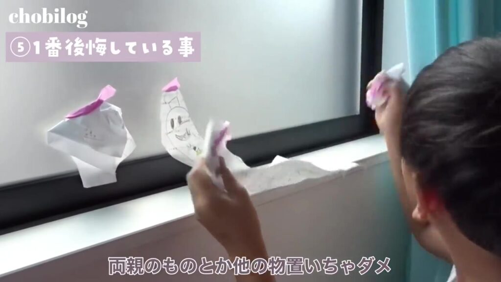 子供部屋の窓に貼った絵を外す子供
