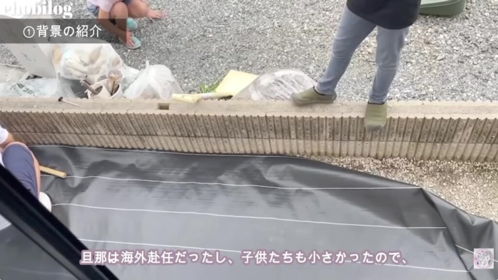 砂利をどかして防草シートを敷く家族の作業